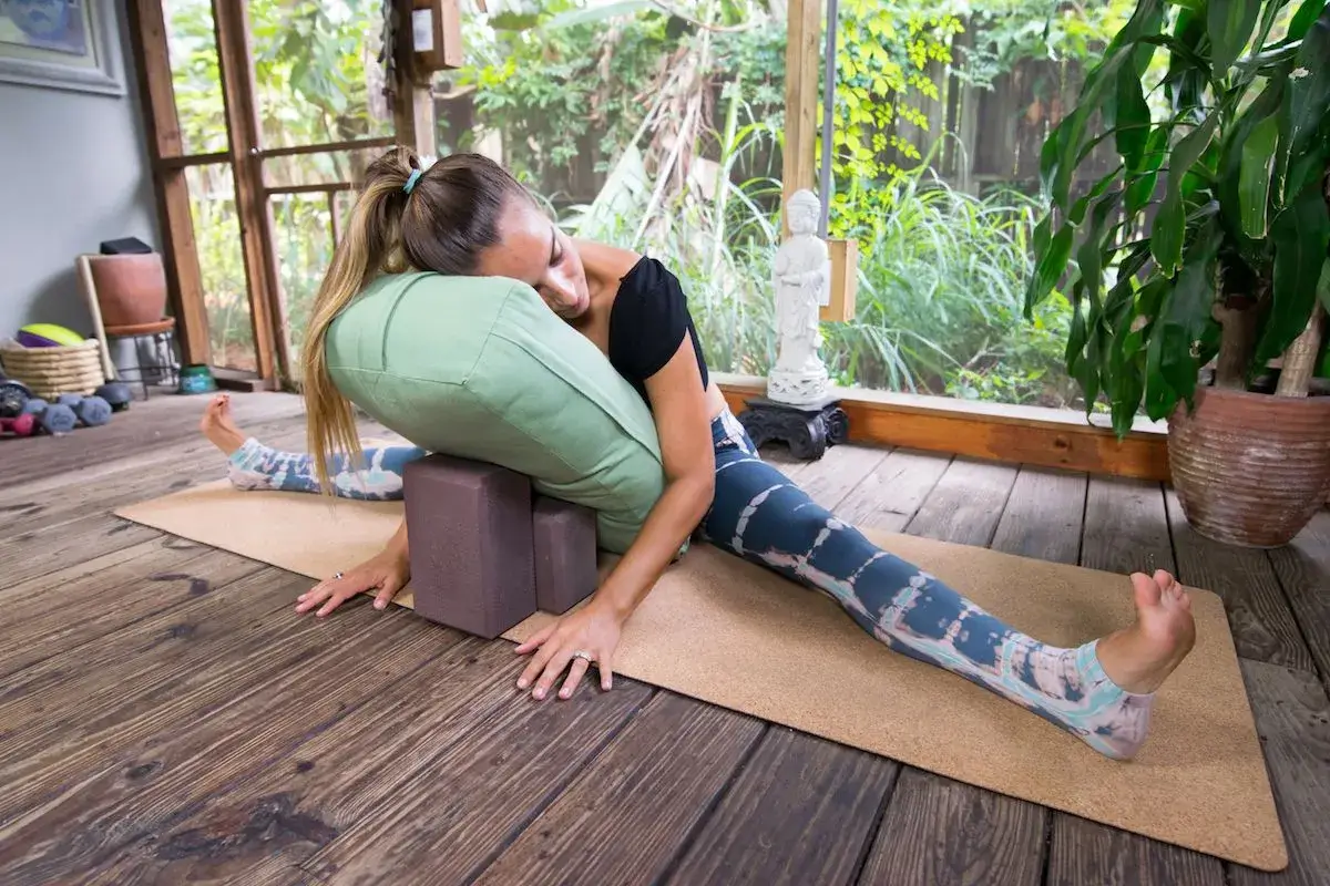 Person relaxing in a restorative yoga pose with props.